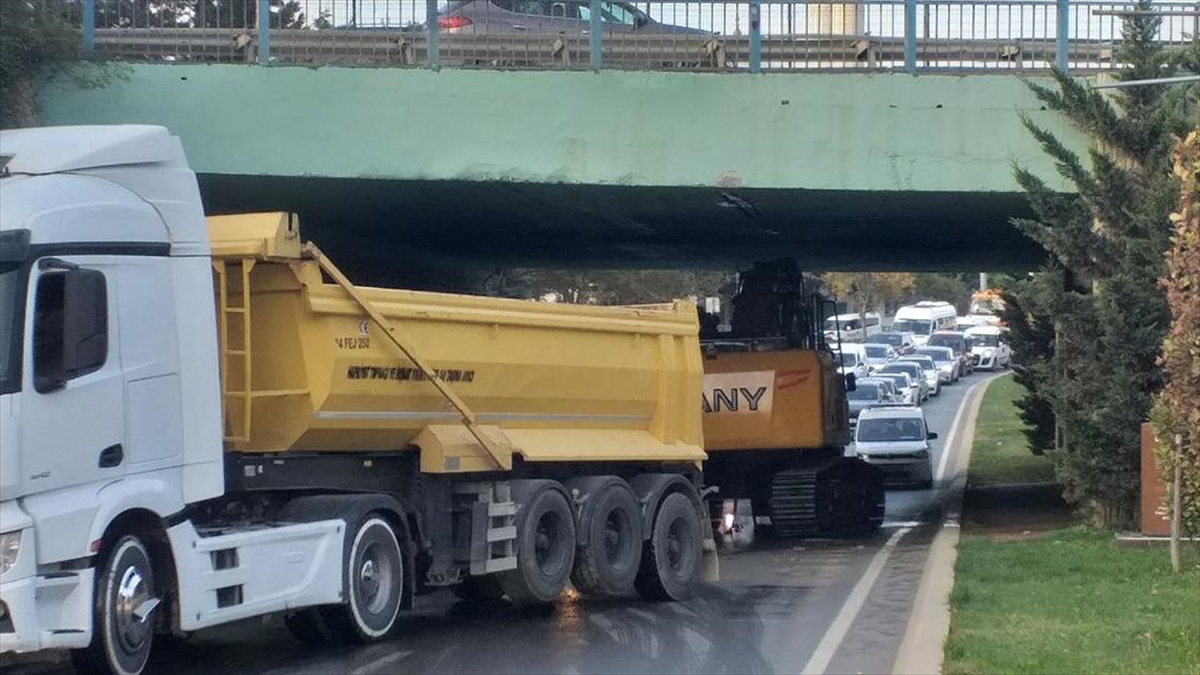 Kartal'da dorsesinde iş makinesi taşıyan tırın köprü altında sıkışması trafik